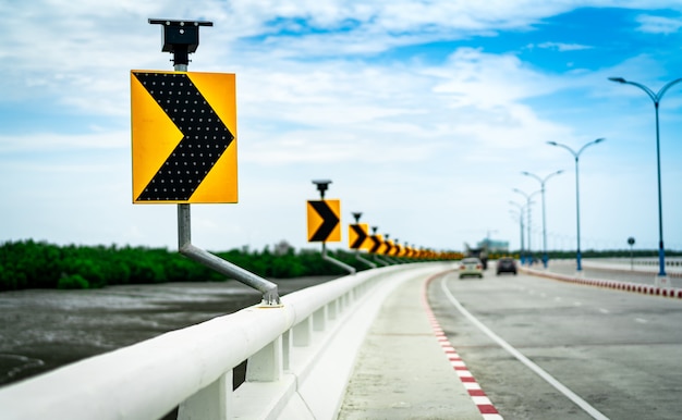 Zwarte en gele pijl op krommeverkeersteken op de brug met zonnecelpaneel