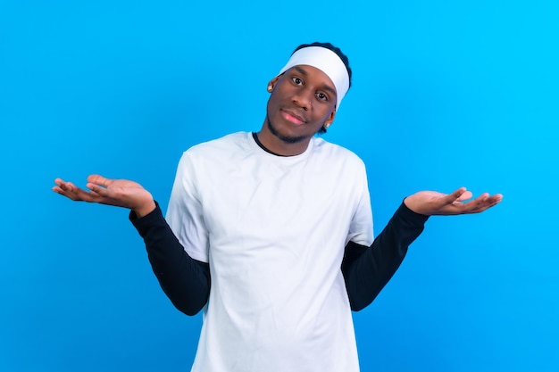 Zwarte etnische man in witte kleren op een blauwe achtergrond die het doordachte gebaar maakt