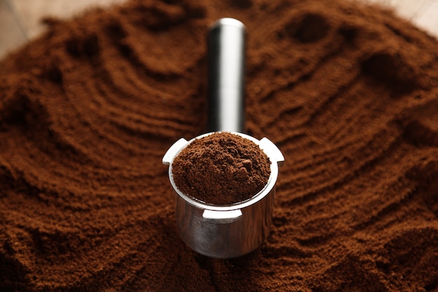 Zwarte gemalen koffie in koffiehouder op koffieachtergrond met textuur