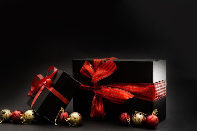 Zwarte geschenkdoos, ballen, rode kerstversieringen op de donkere houten achtergrondkopieerruimte
