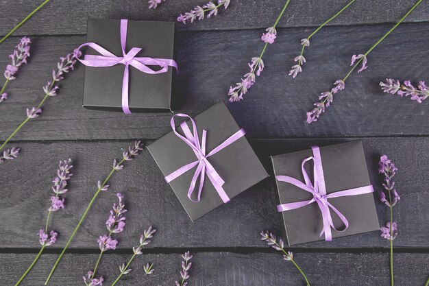 Zwarte geschenkdoos met violet ribbonnd boeket van lavendel bloem op zwart.