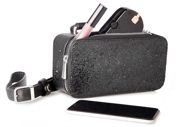 zwarte glanzende tas met cosmetica en smartphone op wit