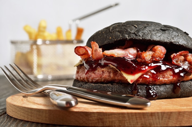 Zwarte hamburger met frietjes op achtergrond