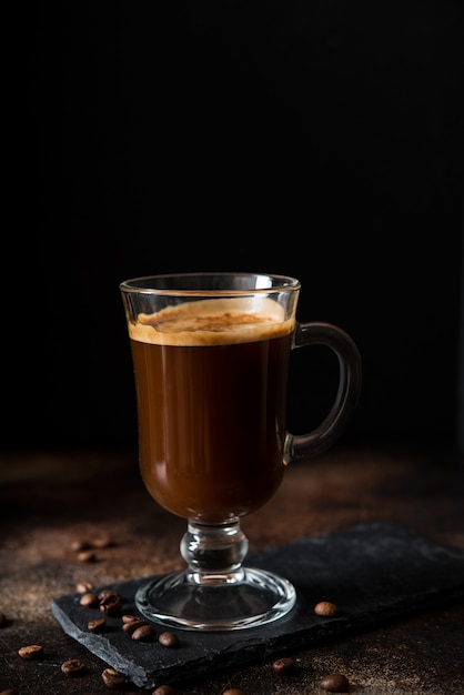 Zwarte hete arabica koffie met schuim in een glasglas op een donkere achtergrond