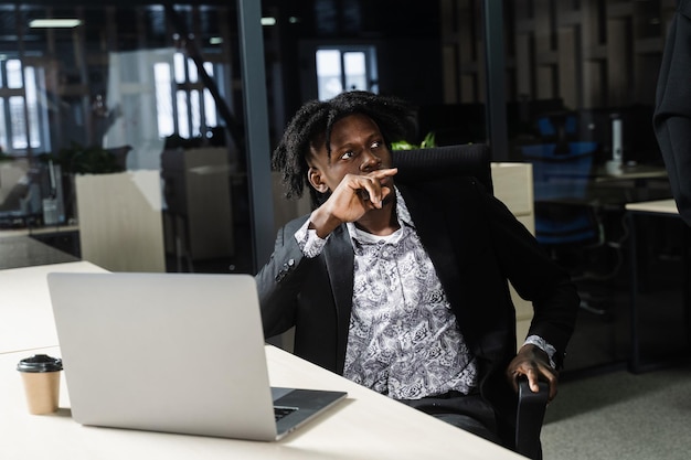 Zwarte hipster man met laptop luistert naar een toespraak van zijn collega's. Teamwerk. Offline baan.