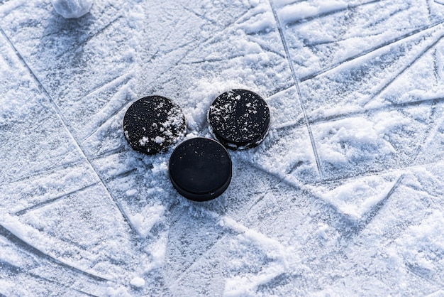 Zwarte hockeypucks liggen op ijs in het stadion
