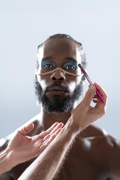 Zwarte homoseksuele met make-up en handen make-up artist met een make-up penseel
