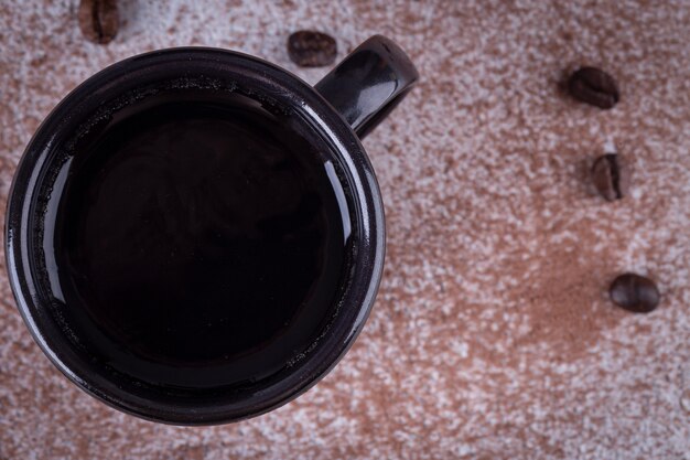 Zwarte ijzeren mok met koffie op tafel