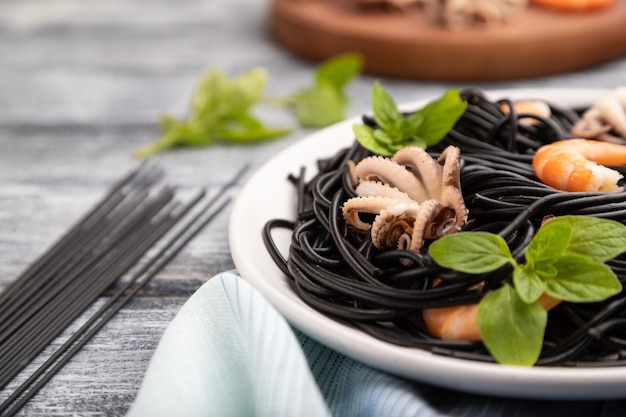 Zwarte inktvisinktpasta met garnalen of garnalen en kleine octopussen op grijze houten achtergrond Zijaanzicht selectieve focus