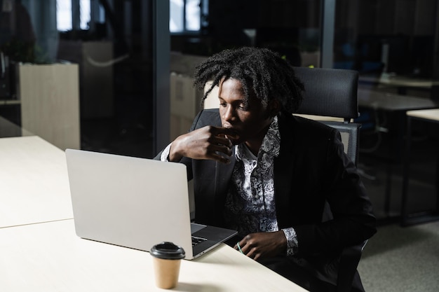 Zwarte IT-programmeur werkt op laptop in coworking space. Knappe Afrikaanse man met laptop op kantoor.