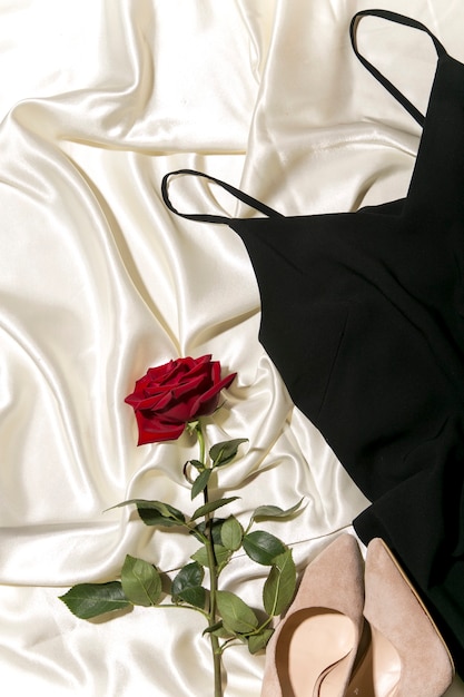 zwarte jurk en rode roos op het bed