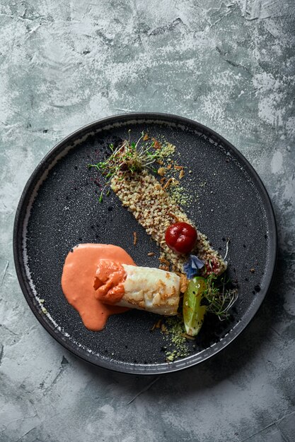 Zwarte kabeljauw steak met tomatensaus en boekweitpopcorn, bovenaanzicht op een bord