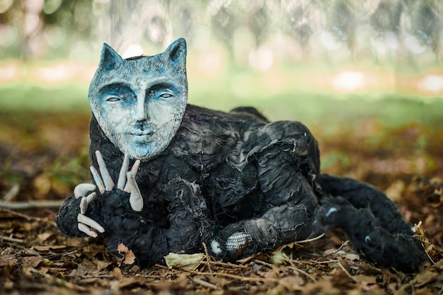 Zwarte kat in menselijk gezichtsmasker kunstobject buitenkunsttentoonstelling in openbaar park raar zwart schepsel