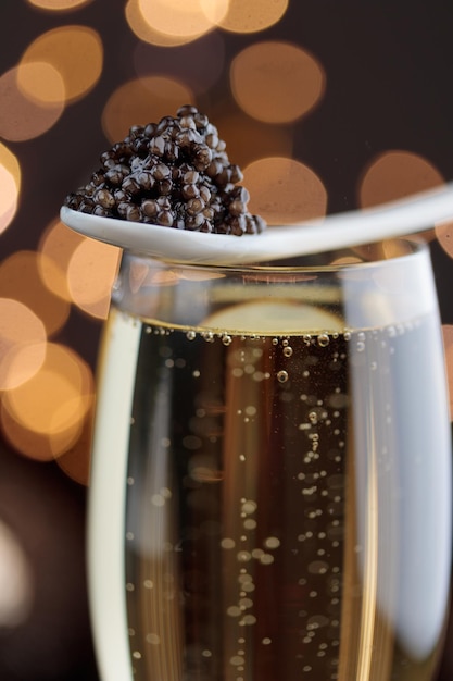 Zwarte kaviaar in een parelmoer lepel en glas champagne met bokeh