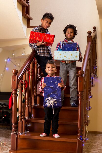 Zwarte kinderen met kerstcadeautjes jongens houden cadeautjes vast op de trap, iedereen zegt kaasmoment...