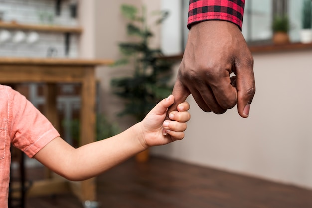 Zwarte kleine zoon met vaders hand