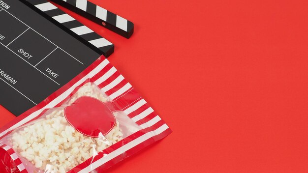 Zwarte klepel bord of film leisteen en rode popcorn tas op rode achtergrond.
