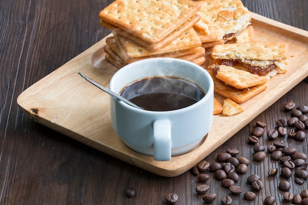 Zwarte koffie, cracker en koffieboon op hout.