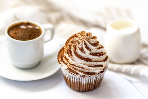 Zwarte koffie, een kopje melk en een spice cupcake met creamchesse en cacao op witte achtergrond