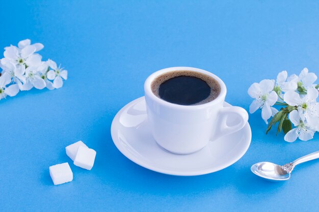 Zwarte koffie in de witte kop en bloeiende boomtakken