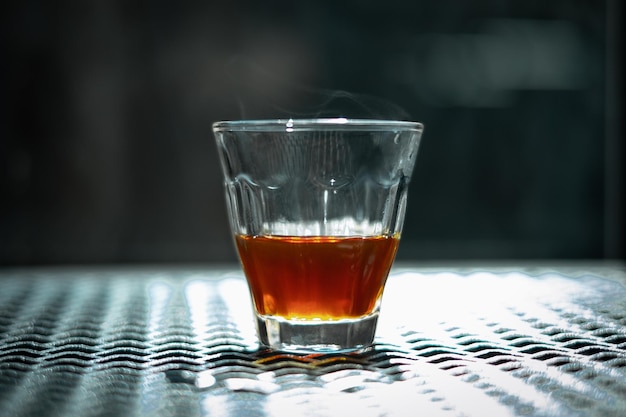 Foto zwarte koffie in glazen beker met rook op stalen tafel