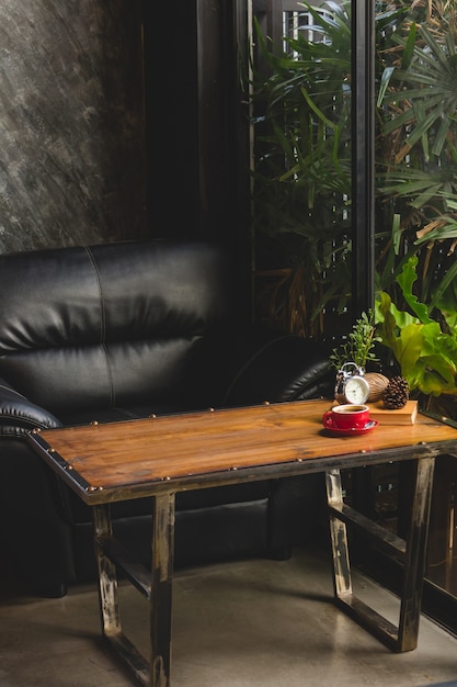 Zwarte koffie in rode kop met boek en klok op tafel in café