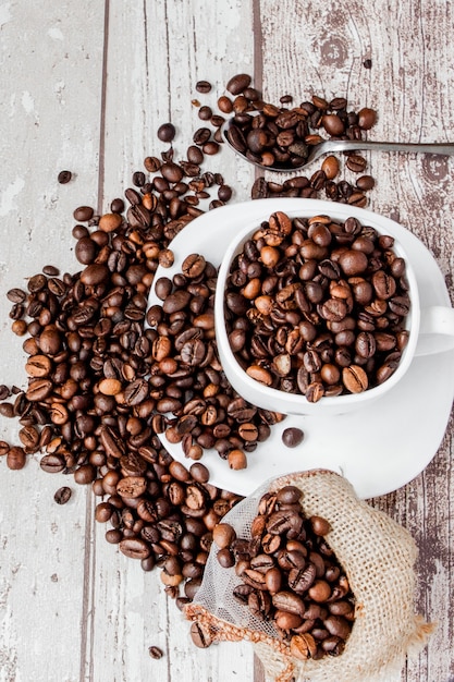 Zwarte koffie in witte kop en koffiebonen op lichte houten