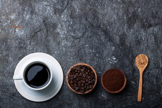 Foto zwarte koffie in witte kopkoffieboon in houten kopsuiker in houten lepel op zwarte steen