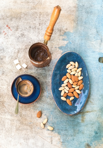 Zwarte koffie met amandelen en pistaches over lichtblauwe tafel. Bovenaanzicht