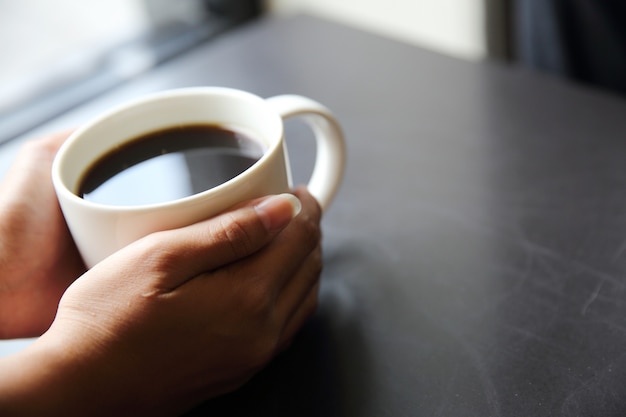 Zwarte koffie met hand op houten achtergrond in coffeeshop
