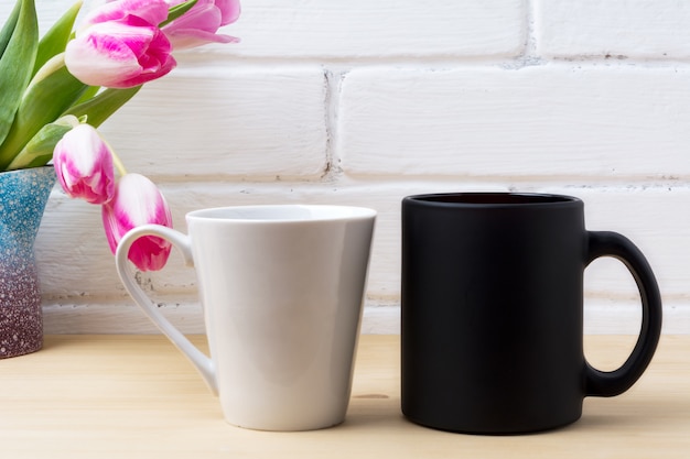 Zwarte koffiekop en witte latte mok met magenta tulp