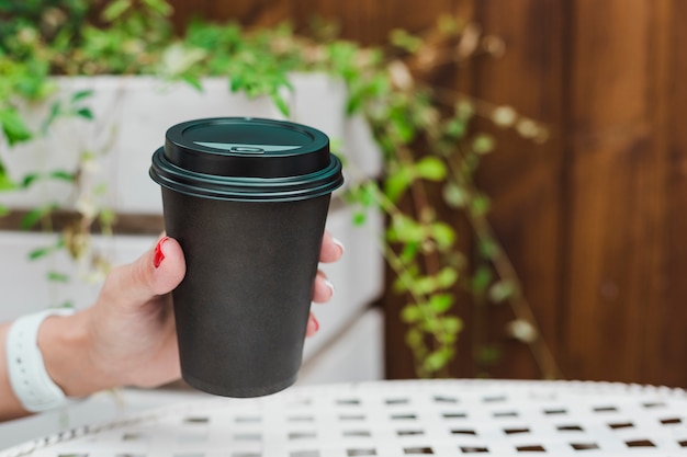 Zwarte koffiekopje in de hand van een vrouw