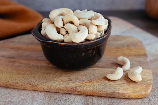 Foto zwarte kom met cashewnoten en gedroogd fruit op houten bord