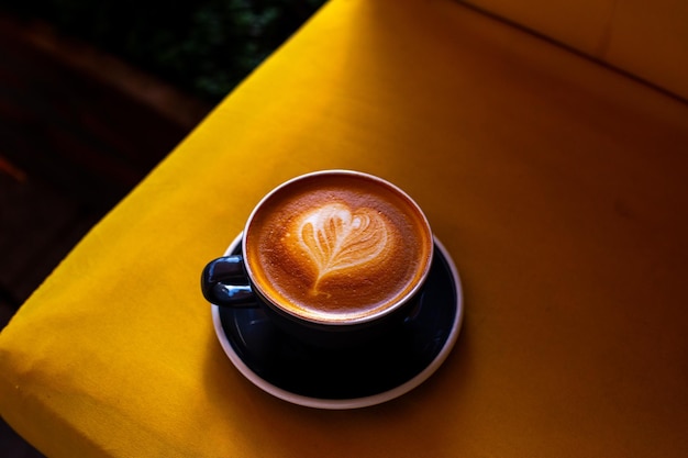 Zwarte kop cappuccino met latte art op houten achtergrond