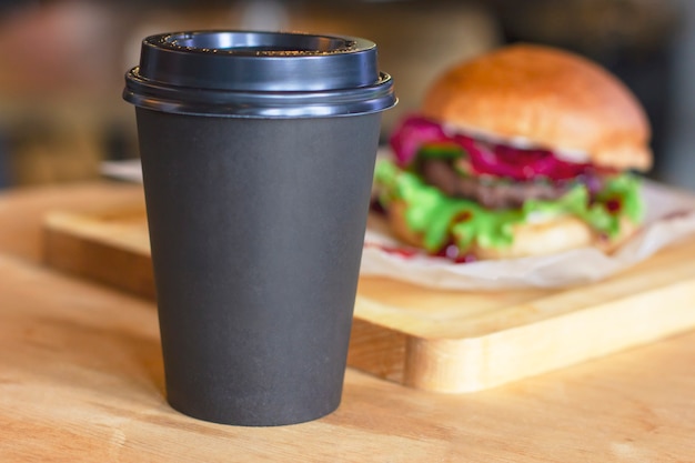 Zwarte kop met koffie om op achtergrond met hamburger te gaan, bespot omhoog