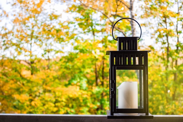 Foto zwarte lantaarn met een kaars op een terrasachtergrond van de herfsttuin