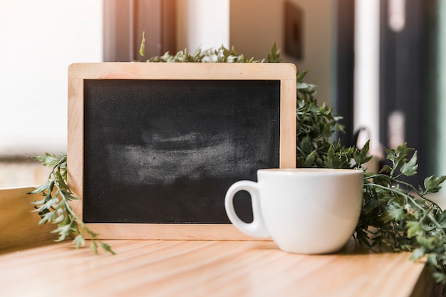 Zwarte lei met kopje koffie op houten bureau