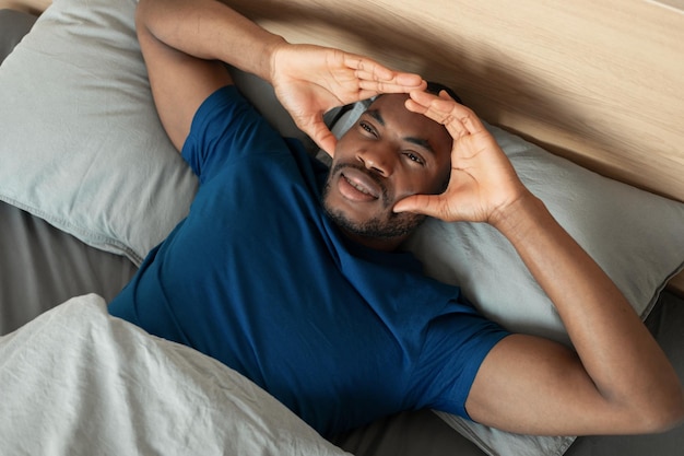Zwarte man die lijdt aan migraine en slapeloosheid die in de slaapkamer ligt