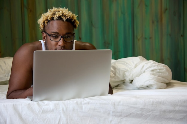 Zwarte man in bed aan het werk met laptop