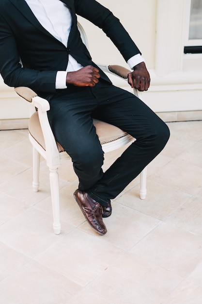 Zwarte man in een pak zittend in een stoel bruidegom zwart leer.
