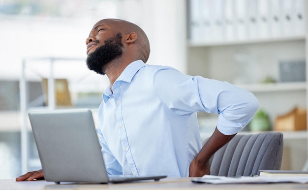 Zwarte man in het bedrijfsleven rugpijn en letsel met gezondheidsprobleem en spierontsteking professional op kantoor en fibromyalgie Mannelijke bedrijfspersoon heeft rugpijn, slechte houding en medisch noodgeval