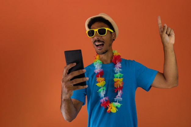 Zwarte man in kostuum voor Brazilië carnaval met mobiel geïsoleerd op een oranje achtergrond. Afrikaanse man in verschillende poses en uitdrukkingen.