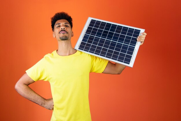 Zwarte man met een spaarvarken en zonnepaneel geïsoleerd op Oranje Man in een geel shirt voor zakelijke onafhankelijkheidsdag