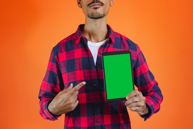 Zwarte man met Junina-feestoutfit met een tablet geïsoleerd op oranje achtergrond Jonge man met traditionele kleding voor Festa Junina Braziliaans juni-festival