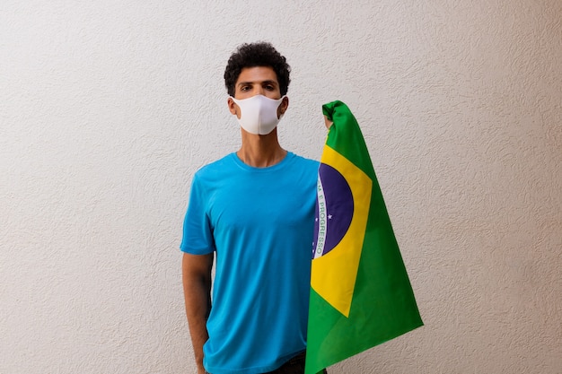 Zwarte man met pandemische masker met een vlag van brazilië geïsoleerd op wit. vlag en onafhankelijkheidsdag concept afbeelding.
