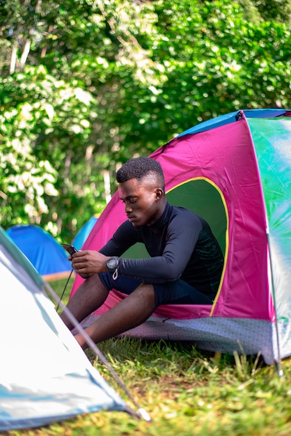 Zwarte man met smartphone buiten de Camping Tent