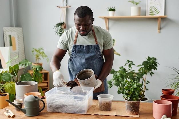 Zwarte man verpot planten binnenshuis en schept verse grondmix