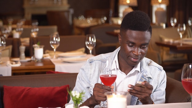 Zwarte mens die rode wijn in restaurant drinkt.