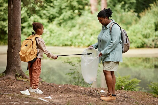 Zwarte moeder en dochter helpen samen de natuur schoon te maken en afval op te ruimen