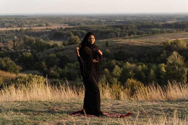 Zwarte moslimvrouw die op het tapijt bidt. Solat bidden op de prachtige heuvel. Salah traditioneel bidden.